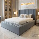 Load image into Gallery viewer, Modern bedroom with a gray upholstered bed and &#39;BEDS N BOARDS&#39; logo.
